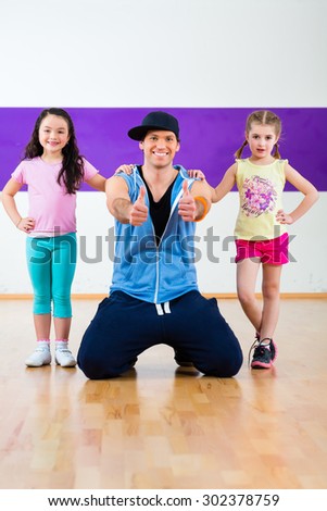 Young dancing teacher training children in modern zumba group choreography