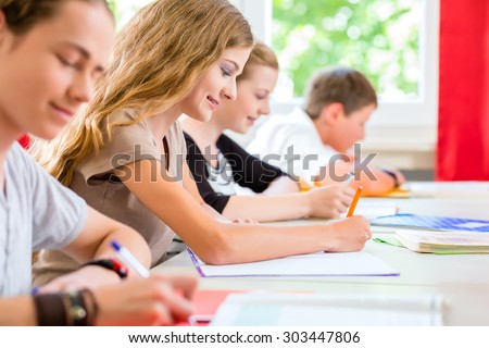 Students or pupils of school class writing an exam test in classroom concentrating on their work