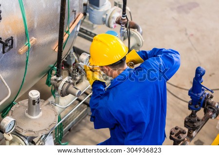 Technician in factory at machine maintenance working with wrench, top view on the man