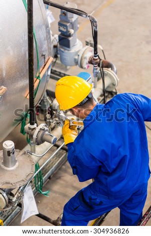 Technician in factory at machine maintenance working with wrench, top view on the man