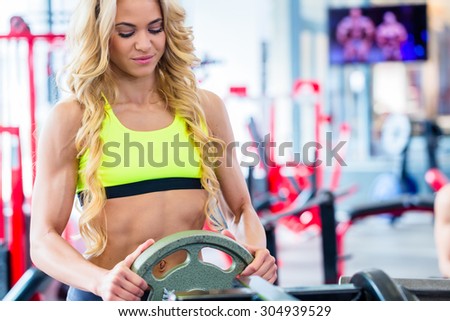 Woman taking weights from stand in fitness gym preparing for training