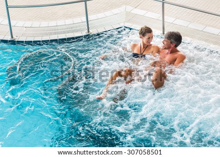 Couple in thermal wellness spa on water massage enjoying the treatment