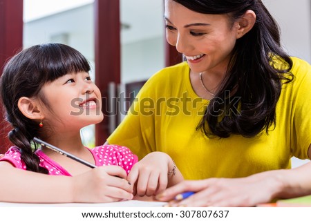 Chinese mother homeschooling her child teaching her daughter to write