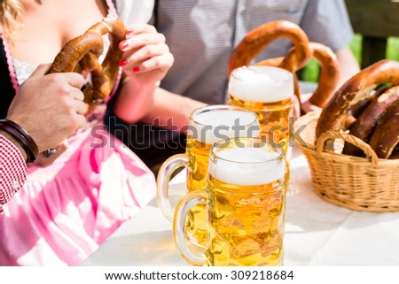 Glasses of beer and pretzel in German beer garden, close-up on the drinks and food