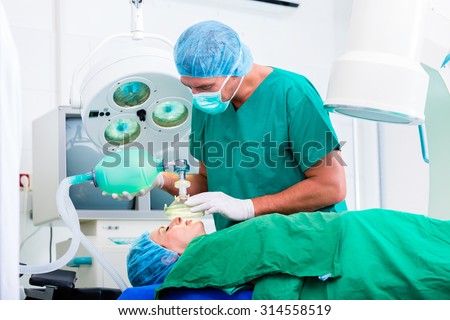 Doctor surgeon with patient in operating room applying anesthetic with mask