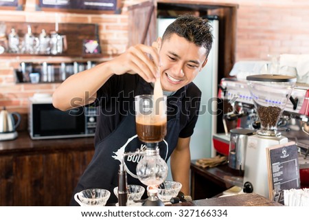 Barista preparing drip coffee in Asian coffee shop using professional machine parts