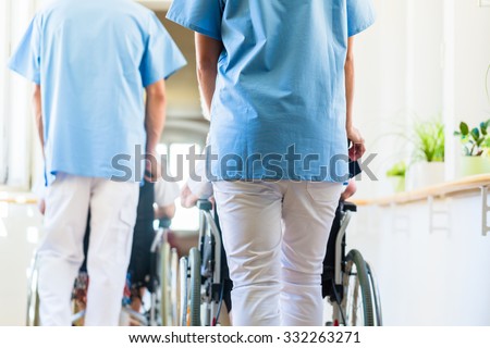 Nurses pushing seniors in wheelchair thru nursing home