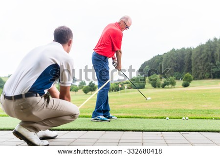 Golf trainer working with golf player on driving range