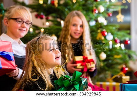 Children with Christmas gift on Christmas day in family home under tree