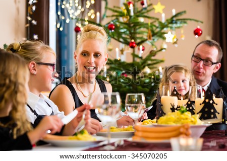 Family of Mother, father, children celebrating Christmas eve with traditional dinner Wiener sausages and potato salad