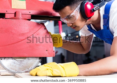 Carpenter in Asian workshop with circular saw in a manufacturing factory