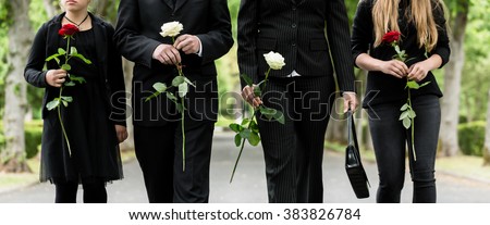 Torso of family on cemetery mourning holding red and white roses in hands
