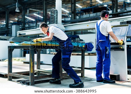Worker team in factory discussing in front of machine