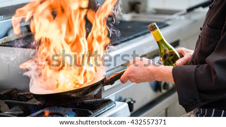 Chef doing flambe to food in pan with alcohol in big flame