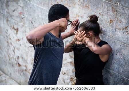 Violent young man threatening his girlfriend with his fist outdoors