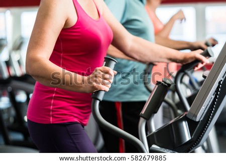 Elderly woman training on cross trainer at the gym