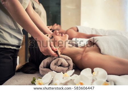 Relaxed woman lying down on massage bed during facial treatment at Asian spa and wellness center