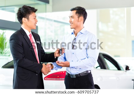 Asian Car Salesman selling auto to customer