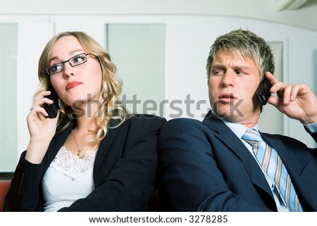 A business man on the phone being quite irritated by a woman also using her phone