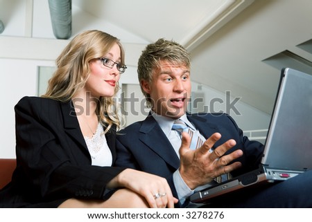 Two business people working on a laptop computer sharing some success