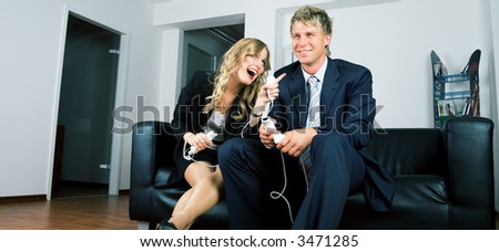 A couple in suits playing videogames, she being more successful that her partner