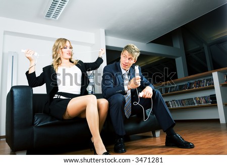 A business couple on a sofa playing electronic games