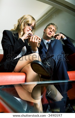A secretary filing her bosses nails, he is smoking and looking rather arrogant