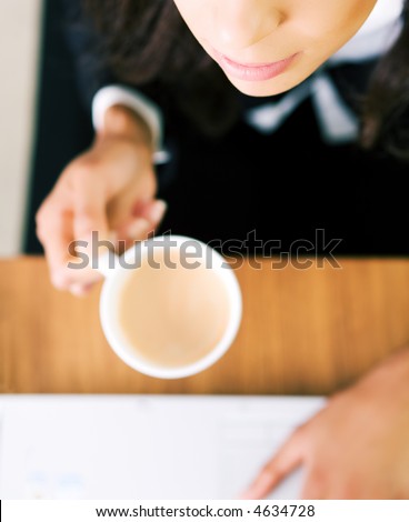 A woman (just hands and parts of face) at her workplace having a double espresso (focus on face)