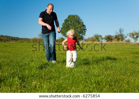 Dad and daughter kicking balls