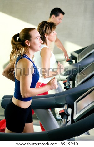 Three rather dynamic people on the treadmill running Three rather dynamic people on the treadmill running