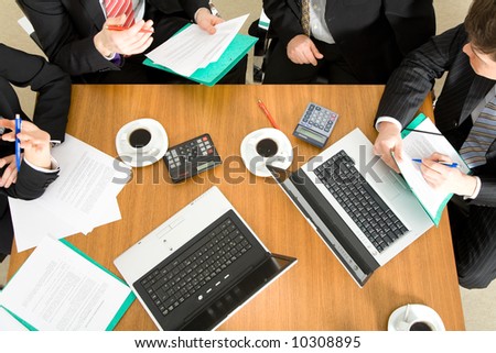 Four people discussing or negotiating a contract – and having a coffee while doing so