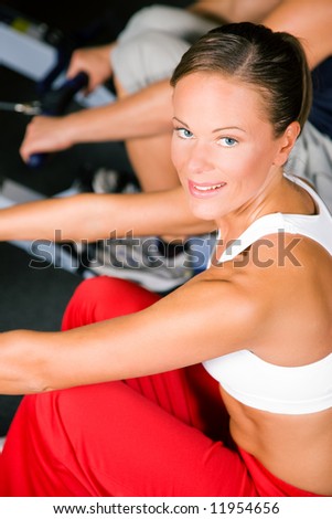 Young woman working out in a gym using a rowing machine