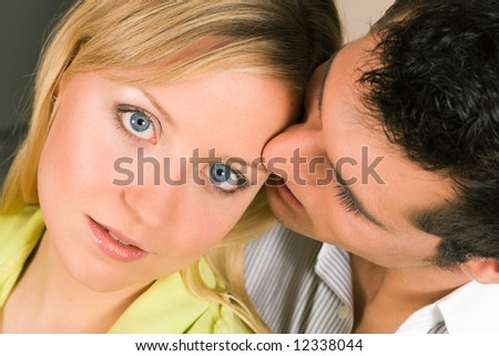 Young man whispering a secret (presumably something very romantic) in her ear