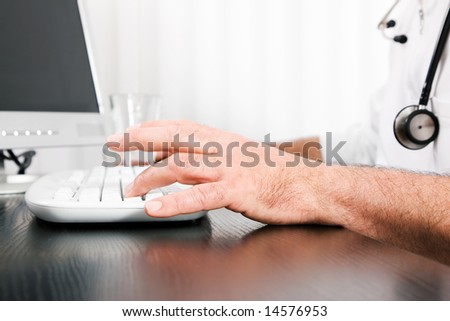 Medical Doctor (only hands to be seen) doing administrative stuff at his computer