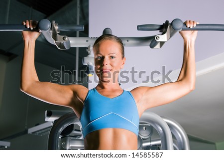 Beautiful woman doing pull-ups on a machine in the gym
