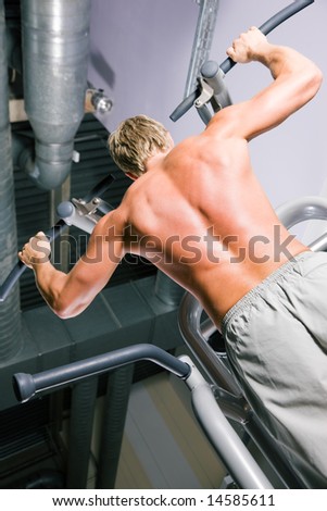 Strong man doing pull-ups on a machine in the gym