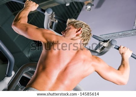 Strong man doing pull-ups on a machine in the gym