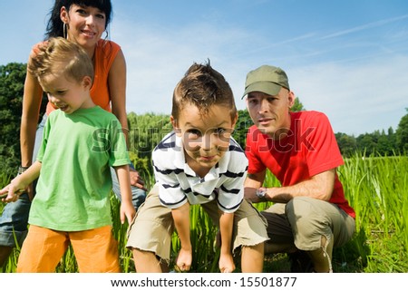 Family having fun, standing at the shore of a lake at a wonderful summer day (focus on the boy in front!)