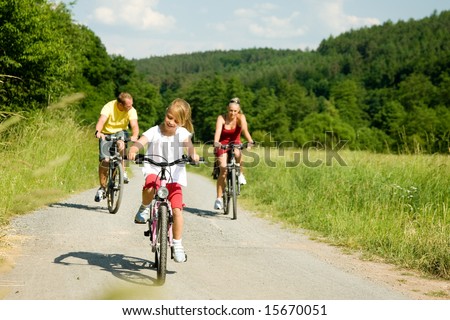 Family with one child riding their bicycles on a summer day (focus on the girl in front)