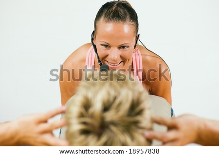 Female fitness trainer in a gym motivating a man to do just one more sit-up