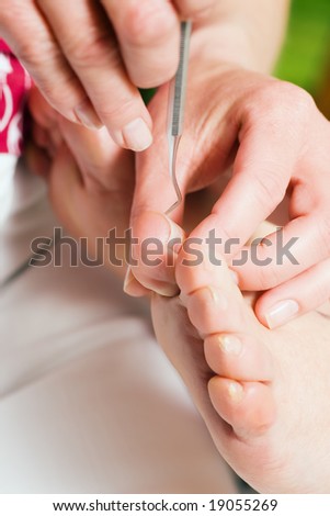 stock photo Woman practicing chiropody taking care of a male feet 