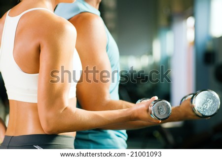 man and a woman (only arms and body) training with dumbbells (focus on weight, shallow depth of field)