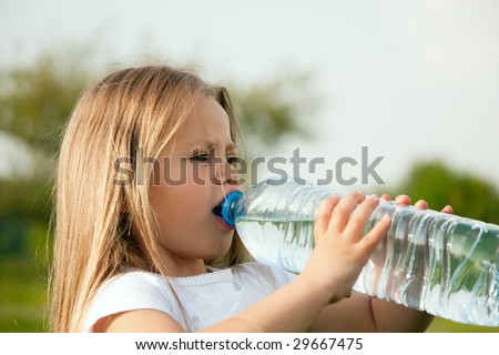 Kid drinking water from a bottle against a sky background