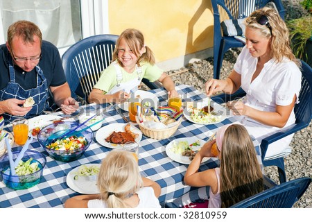 Family having dinner in their garden - barbecue stuff and salad