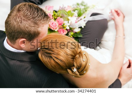 Newlywed couple hugging, the bride holding a bouquet of flowers in her hand