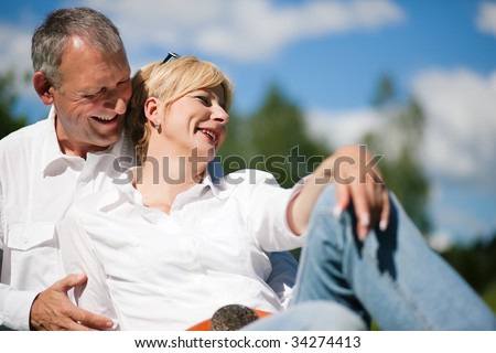 Visibly happy mature or senior couple outdoors arm in arm deeply in love