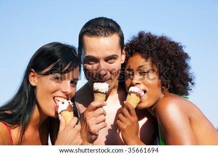 Group of friends - one man and two women eating ice cream in bathing clothes, it seems to be a hot summer day