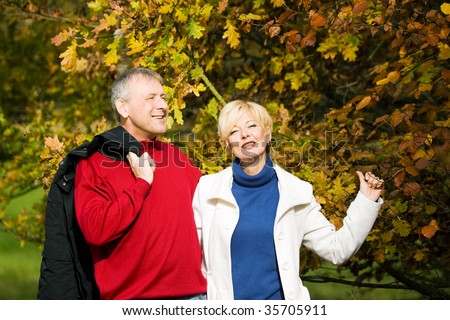 Mature or senior couple deeply in love having a walk holding each other tight in a autumn scenery with yellow leaves