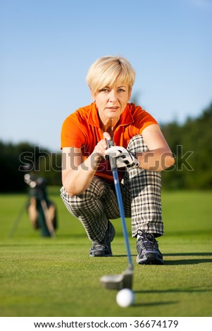 Senior woman playing golf looking and aiming for the hole