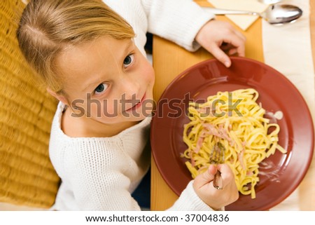 Little girl eating lunch or dinner with her family